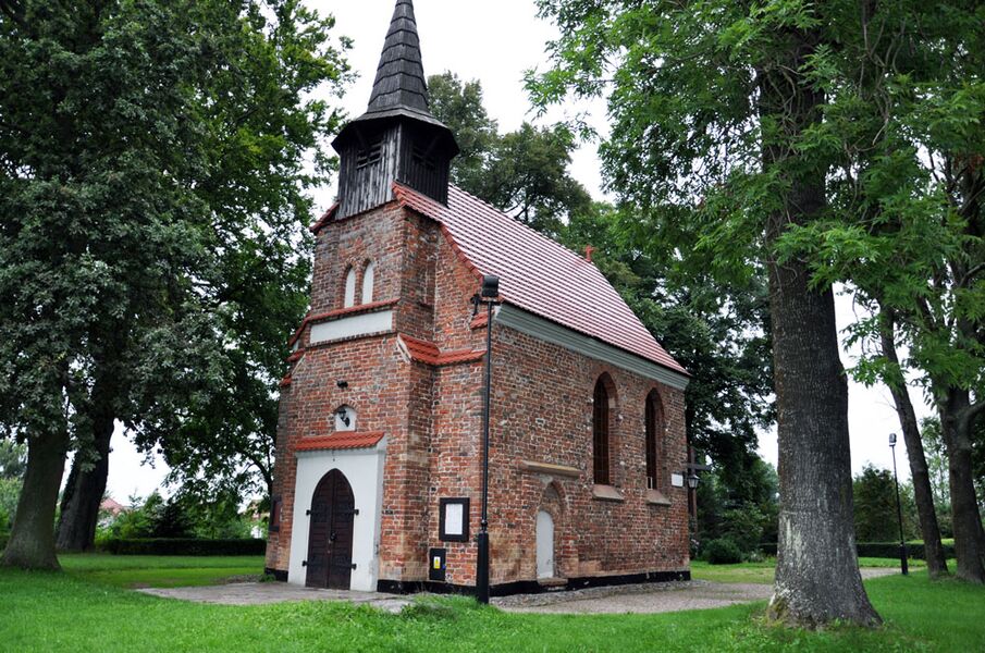 Die Kirche in Budzistowo, Kolberg. Foto einer alten kleinen Backsteinkirche im Grünen: Kolberg-Café