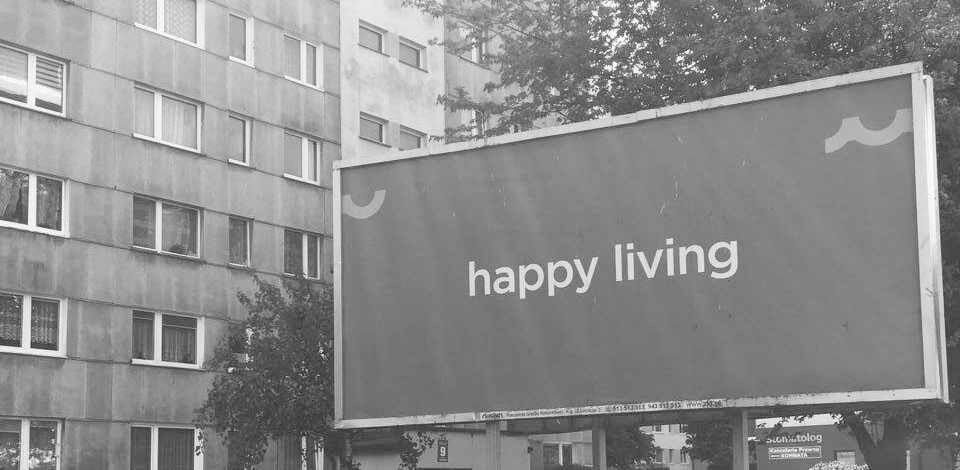 Plakat "Happy Living" vor einem Kolberger Plattenbau. Foto: Kolberg-Café