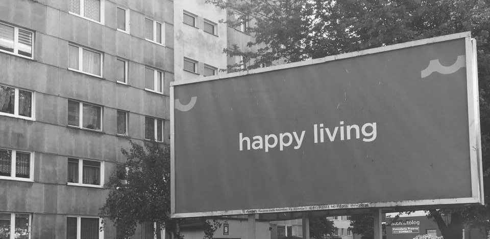 Plakat "Happy Living" vor einem Kolberger Plattenbau. Foto: Kolberg-Café