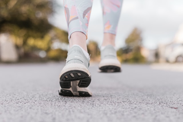 Schuhe auf dem Asphalt, laufend, mit bunten Leggings an den Beinen der tragenden Person. Foto: Sincerely Media via Unsplash